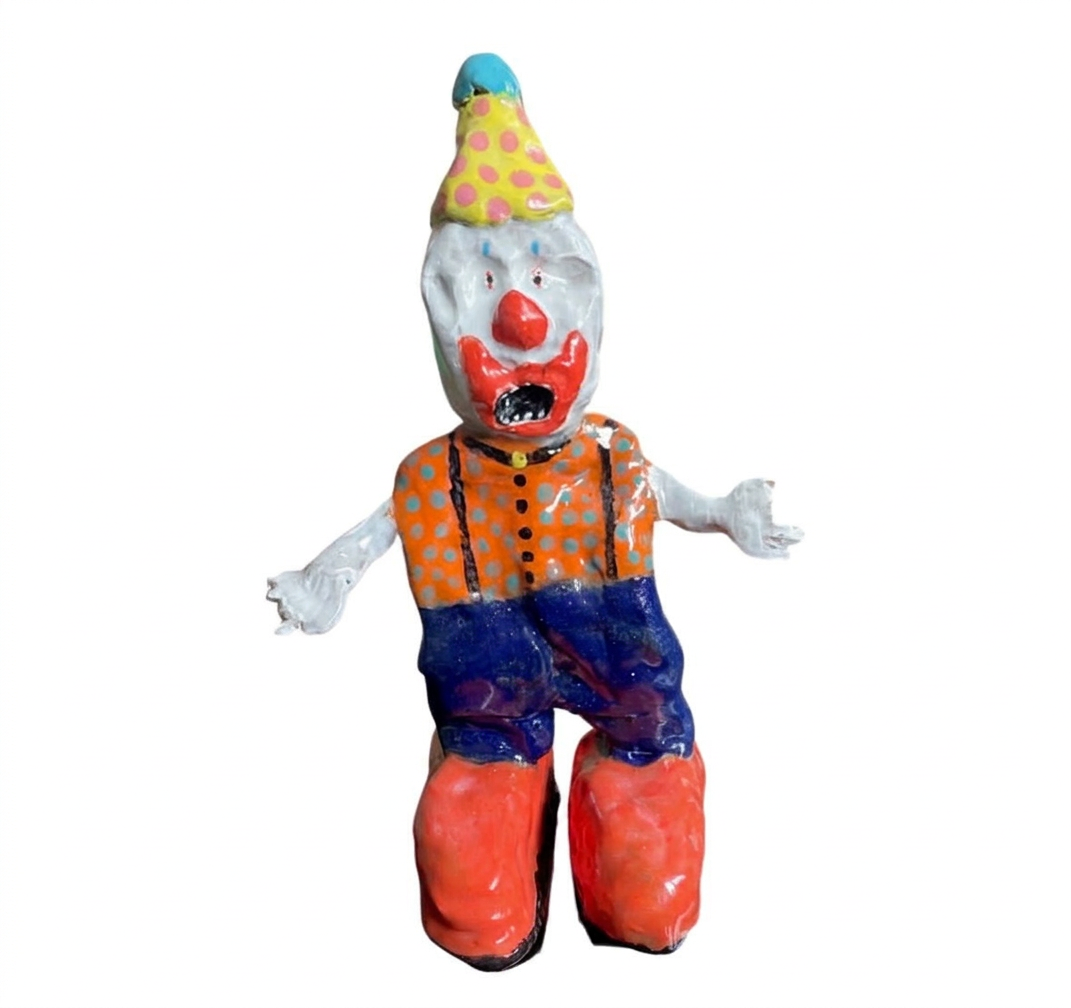 Ceramic screaming clown figure with yellow polka-dot hat, orange polka-dot shirt and red shoes