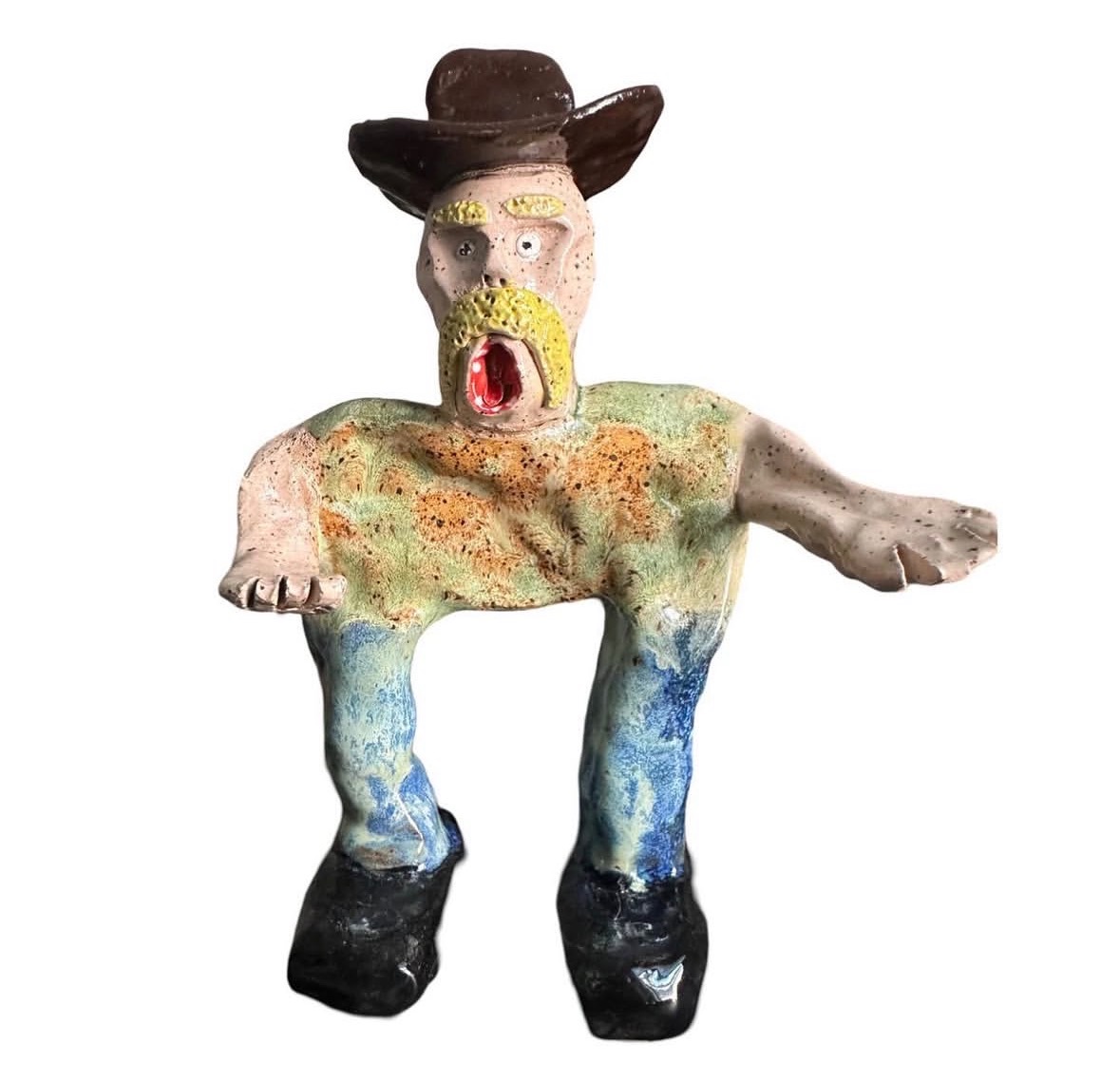 Ceramic cowboy figure with brown hat, yellow mustache, green shirt and blue pants