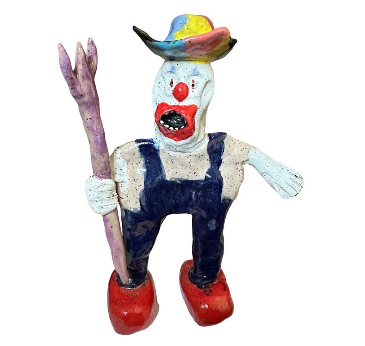 Ceramic clown farmer figure with rainbow hat, overalls and pitchfork