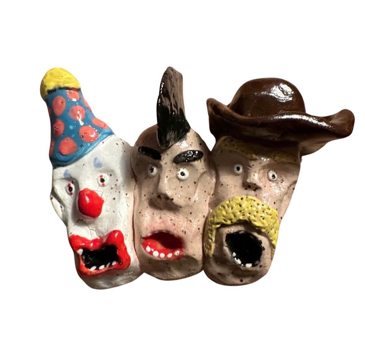 Ceramic wall sculpture with row of three heads — clown with polka-dot hat, mohawk punk and blond cowboy