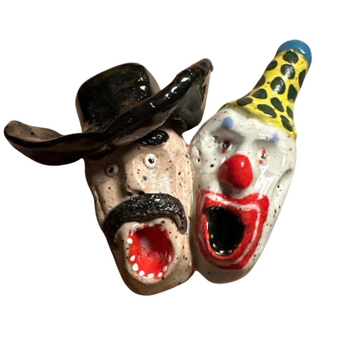 Ceramic wall sculpture pairing a screaming mustachioed cowboy in black hat with a screaming clown in yellow polka-dot hat