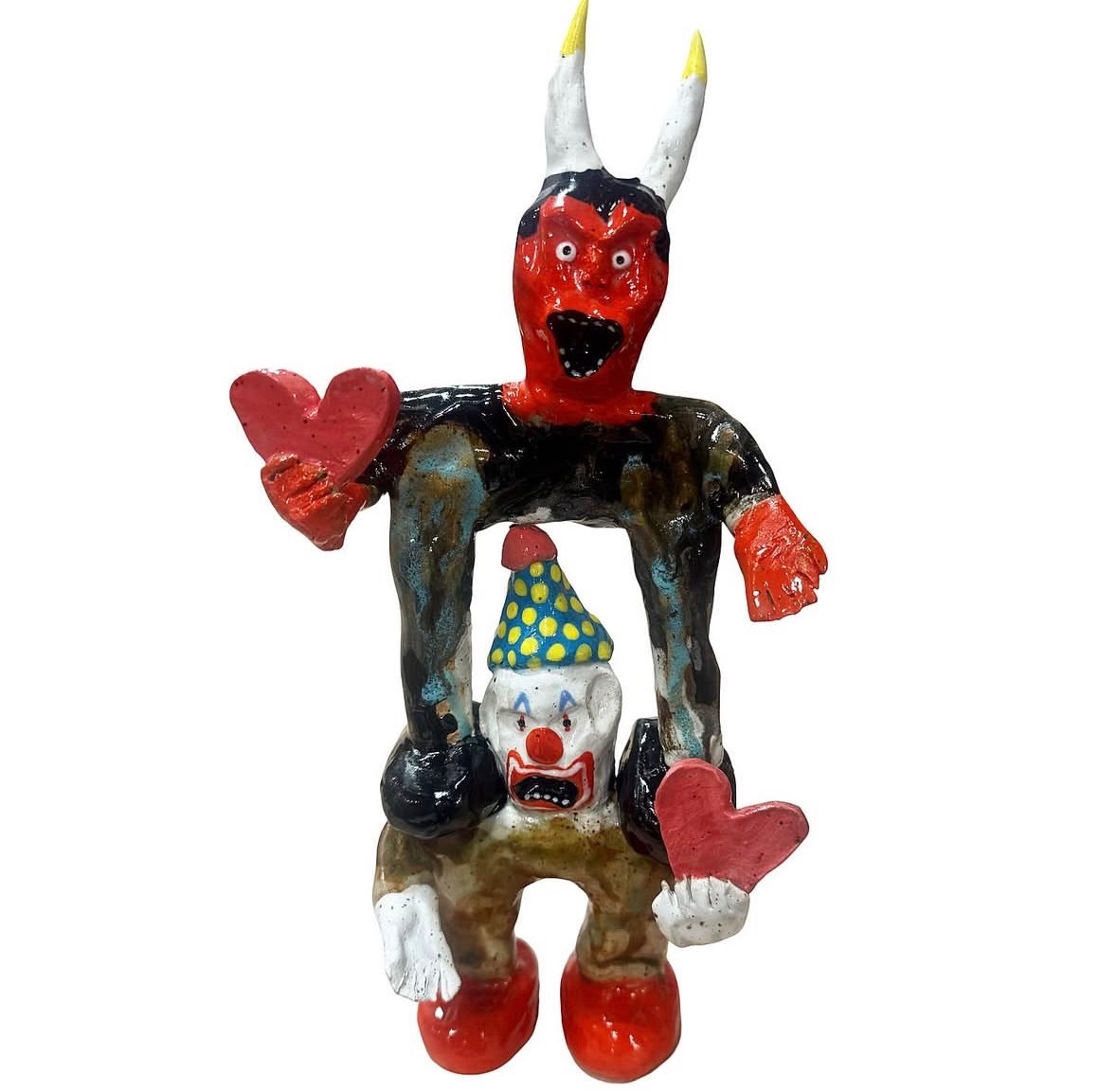 Ceramic horned devil figure standing over screaming clown