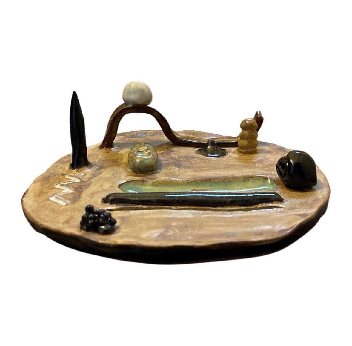 Ceramic landscape sculpture side view with tree, arched bridge, figures and dark stone