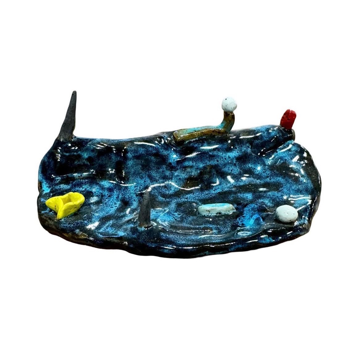 Ceramic blue-glazed landscape sculpture side view with dark spire, yellow flower and small figures